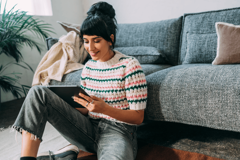 A beautiful woman being entertained by watching something on her tablet.