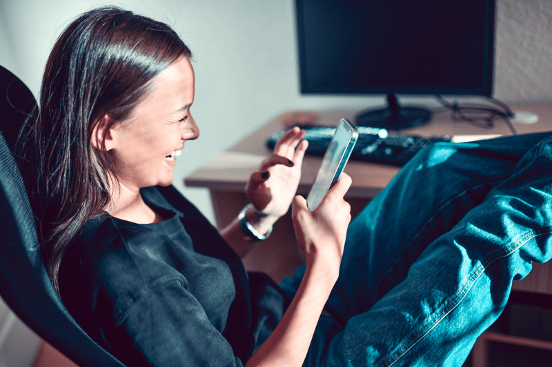 Smiling Female Checking Funny Photos On Smartphone Online