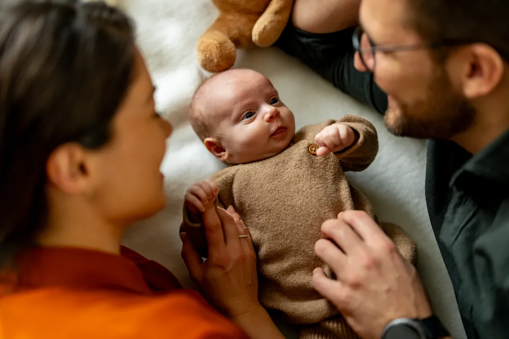 Happy parents playing with their newborn son on bed